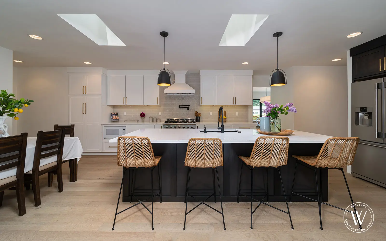 Hemlock kitchen after: open white kitchen with a black island, quartz counters, skylights and white-oak floors