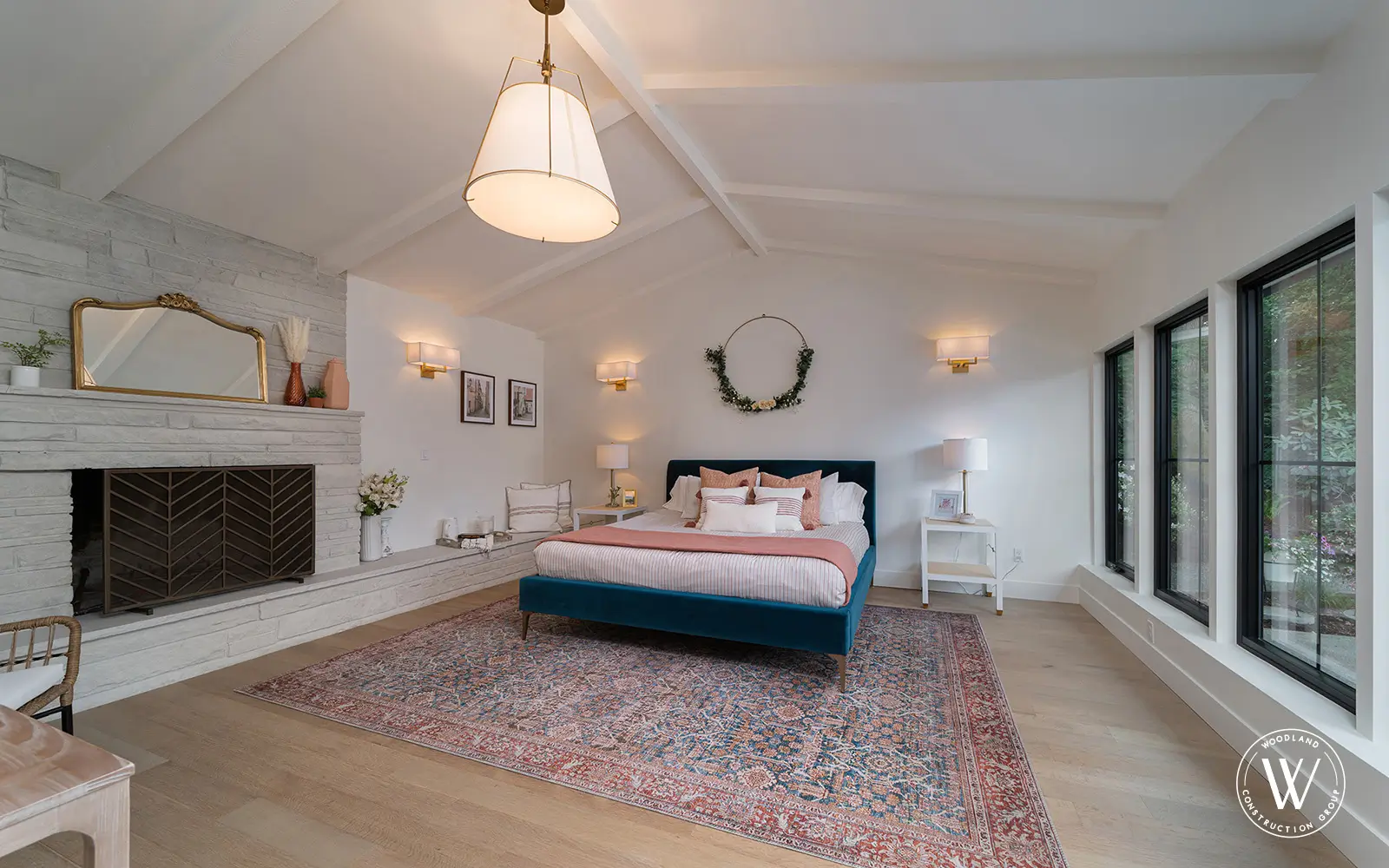 Hemlock primary bedroom after: bright vaulted ceiling, whitewashed brick fireplace and black-framed windows