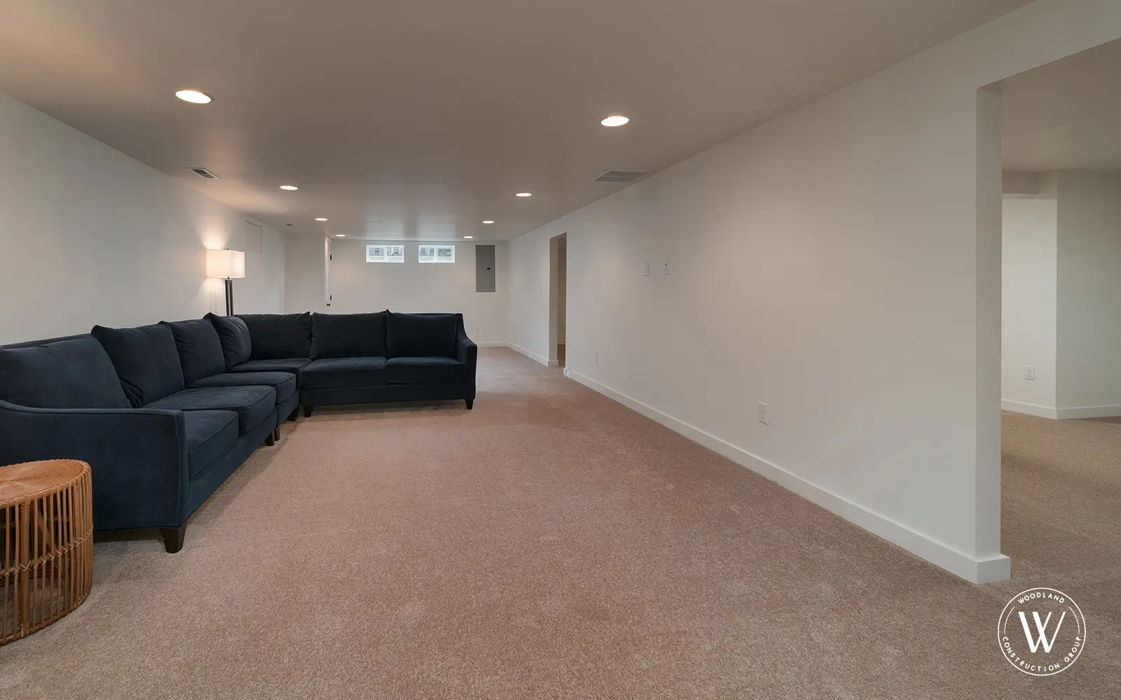 Hemlock basement after: finished, carpeted family room with recessed lighting and egress windows