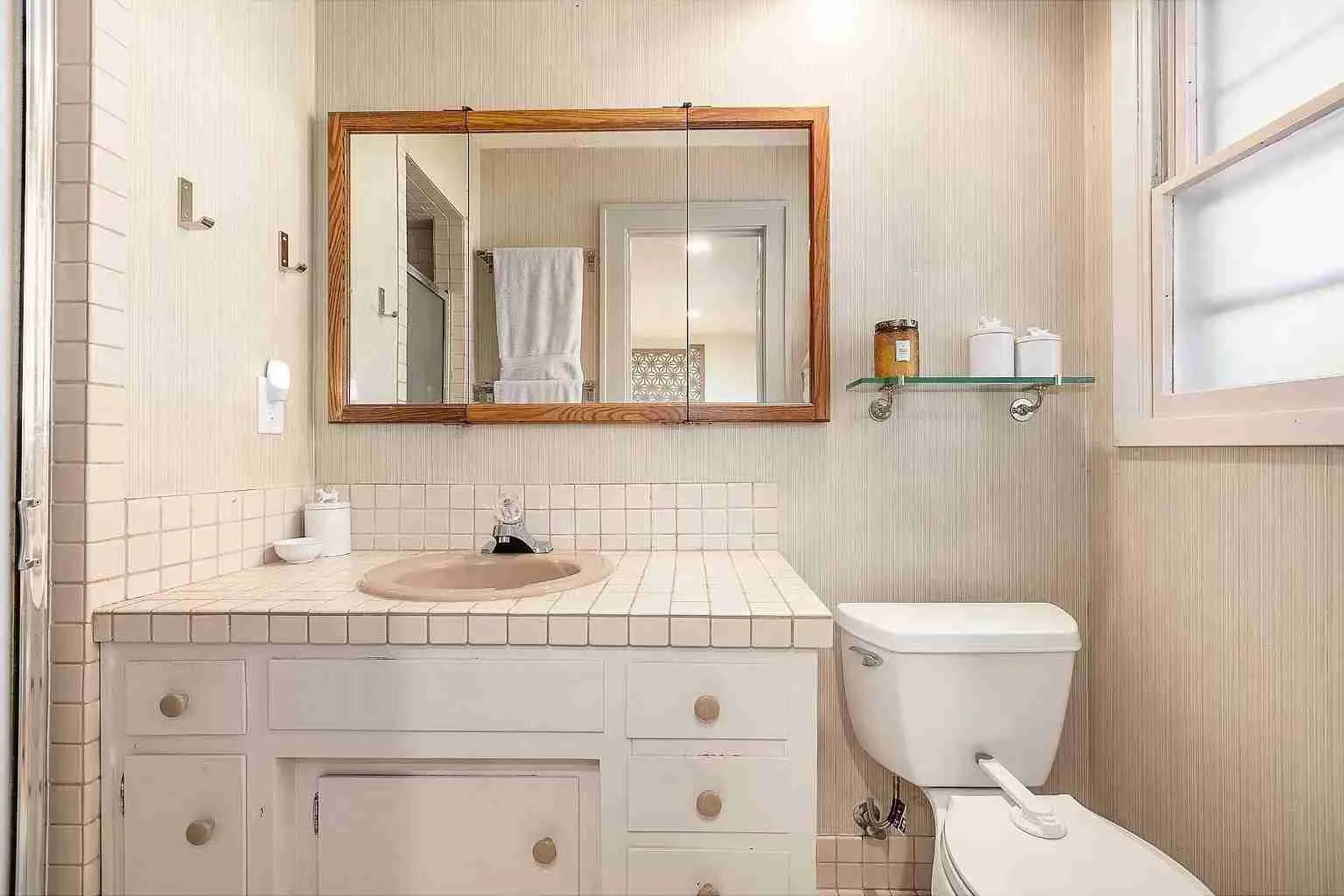 Berkshire bathroom before remodel, dated tile-topped vanity with an almond drop-in sink and an oak medicine cabinet, Portland Oregon