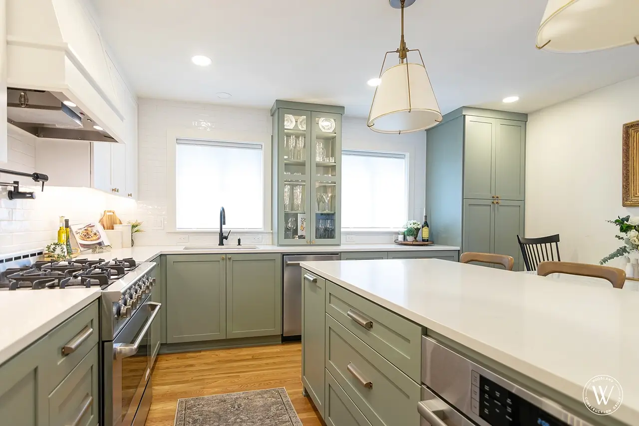 Sherwood sink wall after: sage-green cabinetry, a black faucet and a tall glass display cabinet