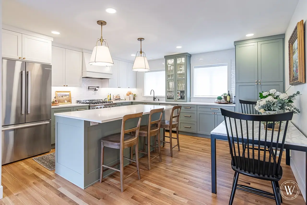 Sherwood kitchen after: the custom island open to a dining area with pendant lighting and white-oak floors
