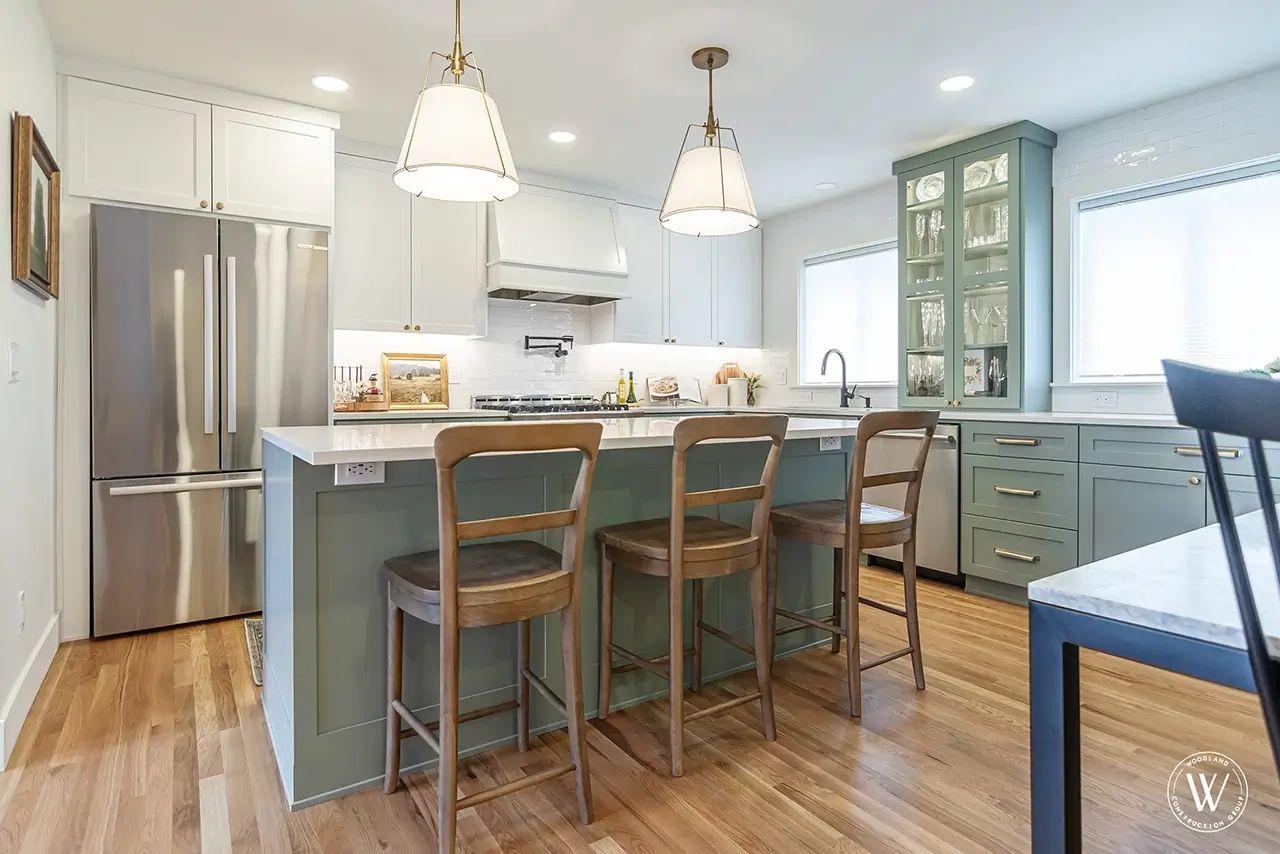 Sherwood kitchen after: open sage-green kitchen with a custom island, white uppers, quartz counters and white-oak floors