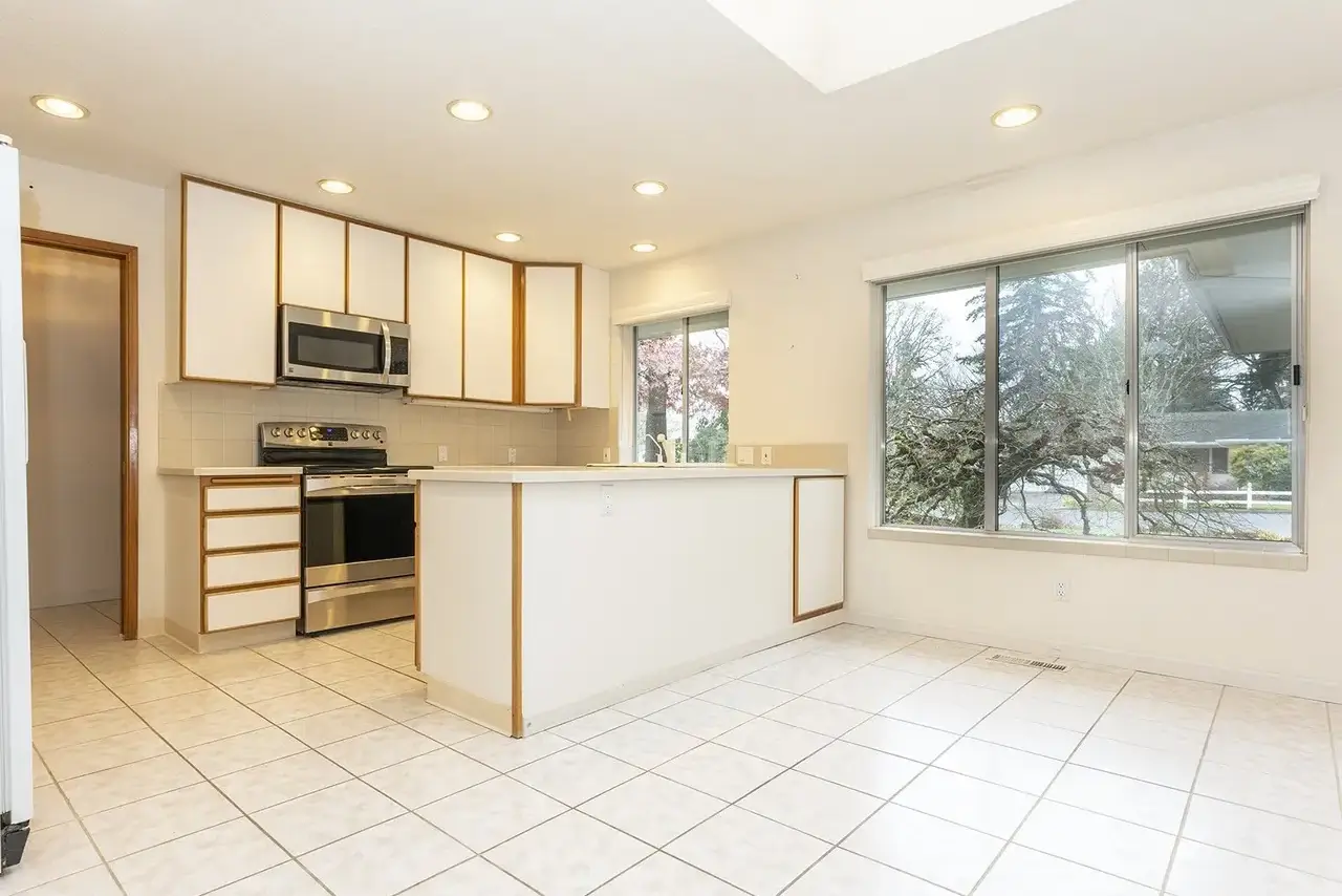 Sherwood kitchen before: dated white-laminate and oak-trim cabinets, tile floor and a closed-off peninsula