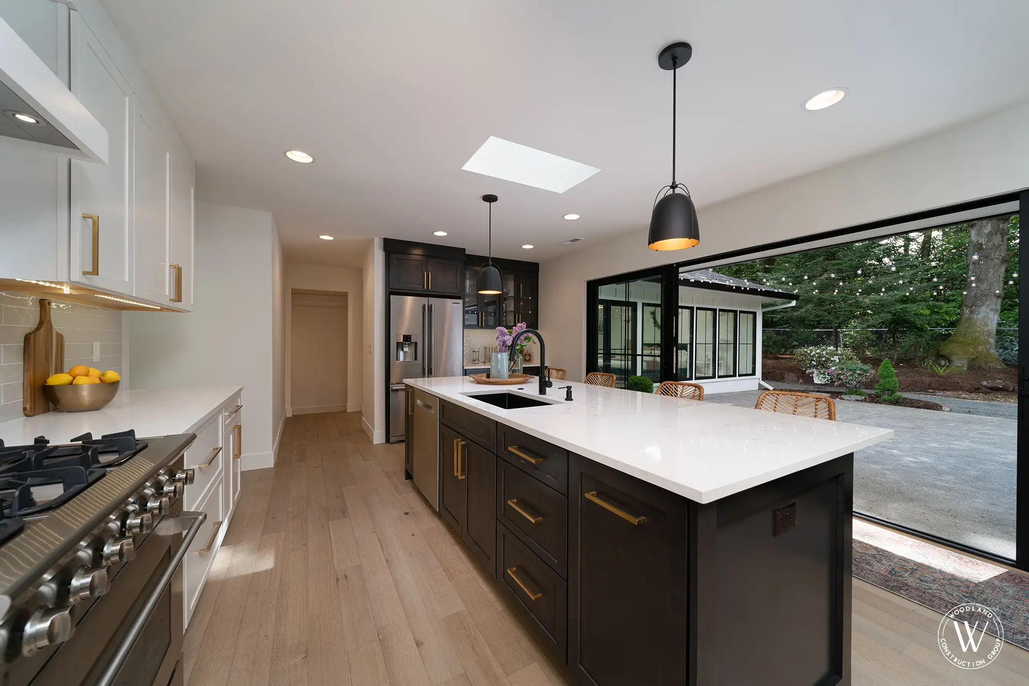 Whitepine kitchen with white perimeter cabinetry, a dark quartz island, professional gas range and open sliding doors