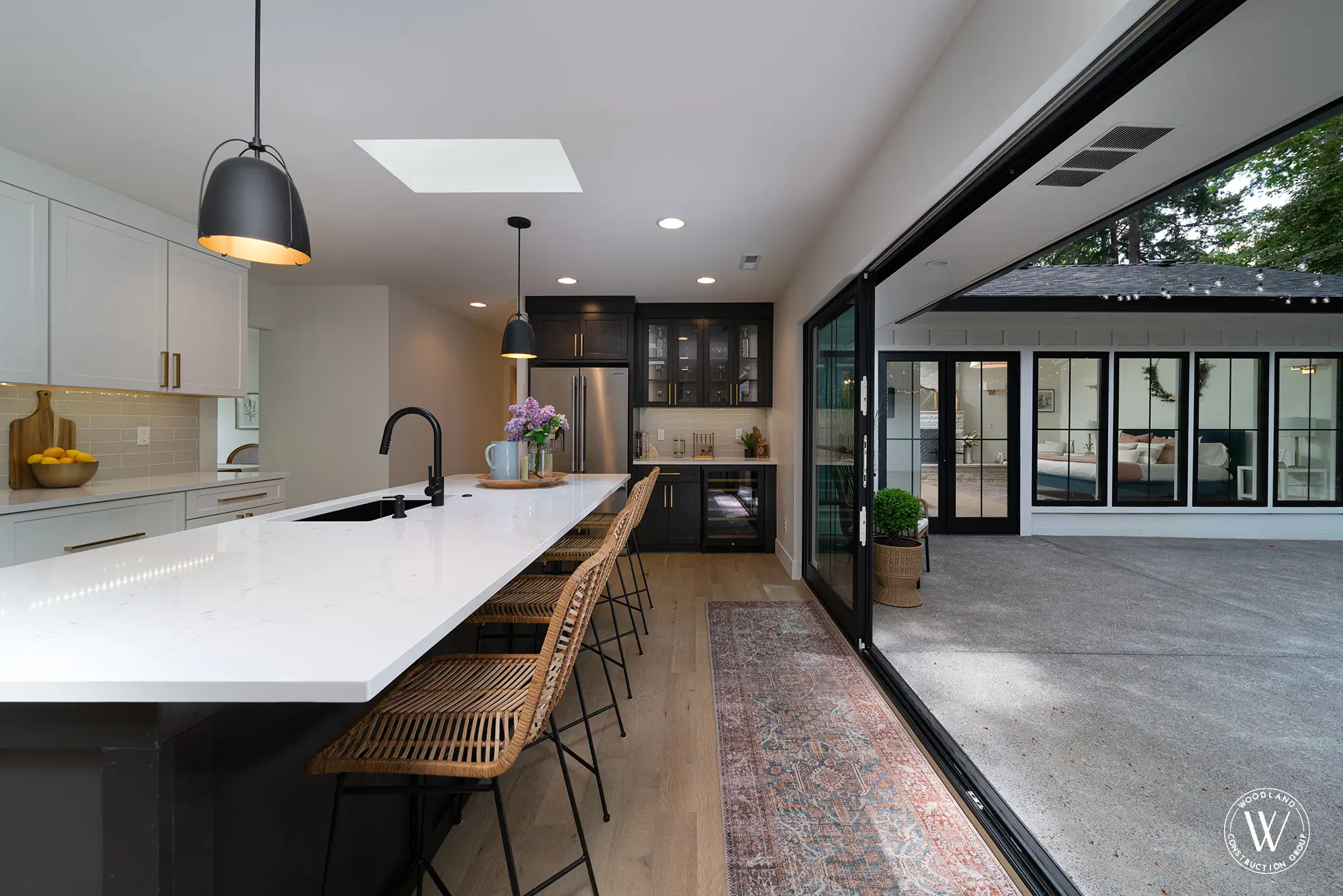 Restored Whitepine kitchen with a quartz entertainer's island, black gooseneck faucet and 16-foot sliding doors to the courtyard, SW Portland