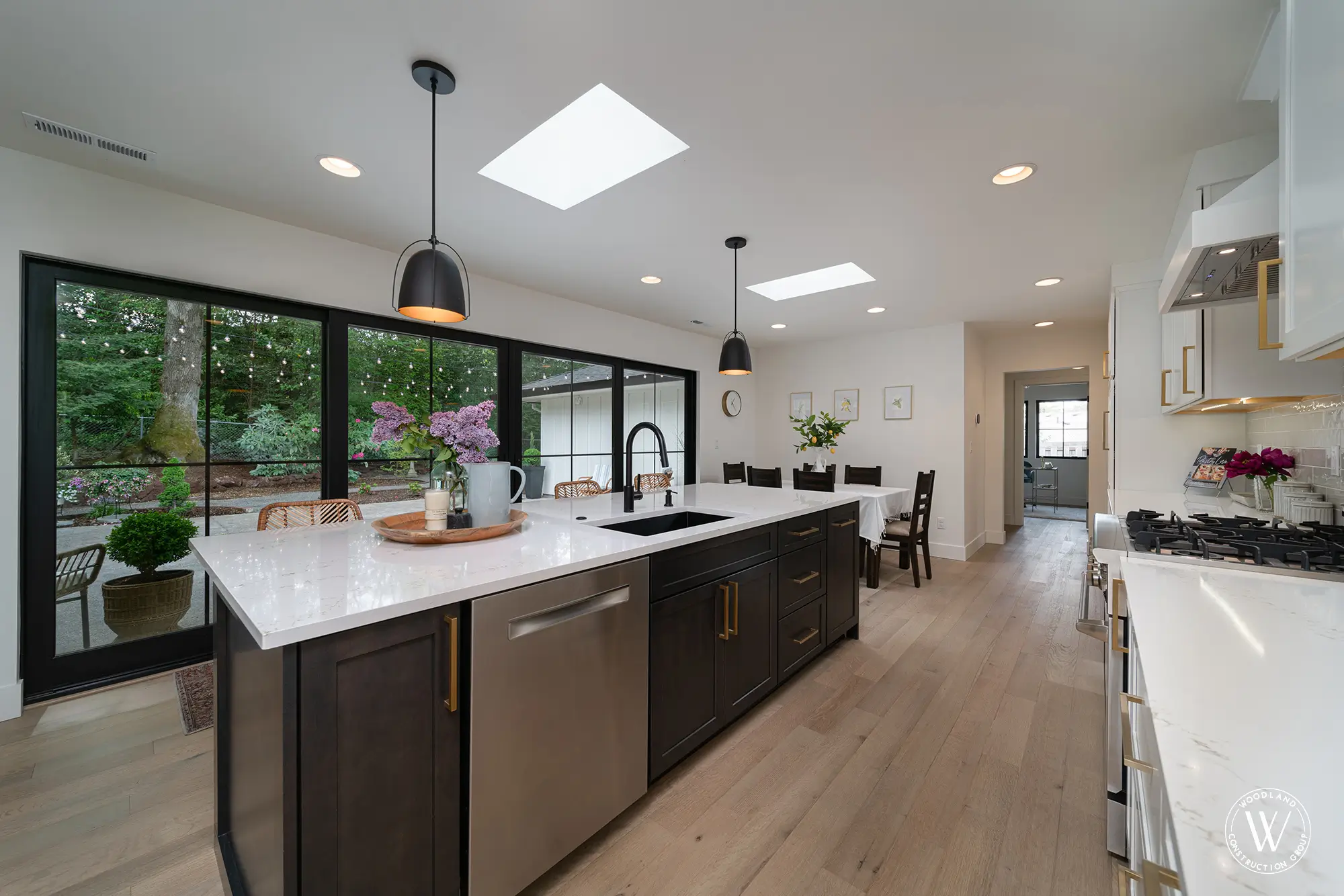 Whitepine kitchen island with a black prep sink and gooseneck faucet, open to the dining area and garden