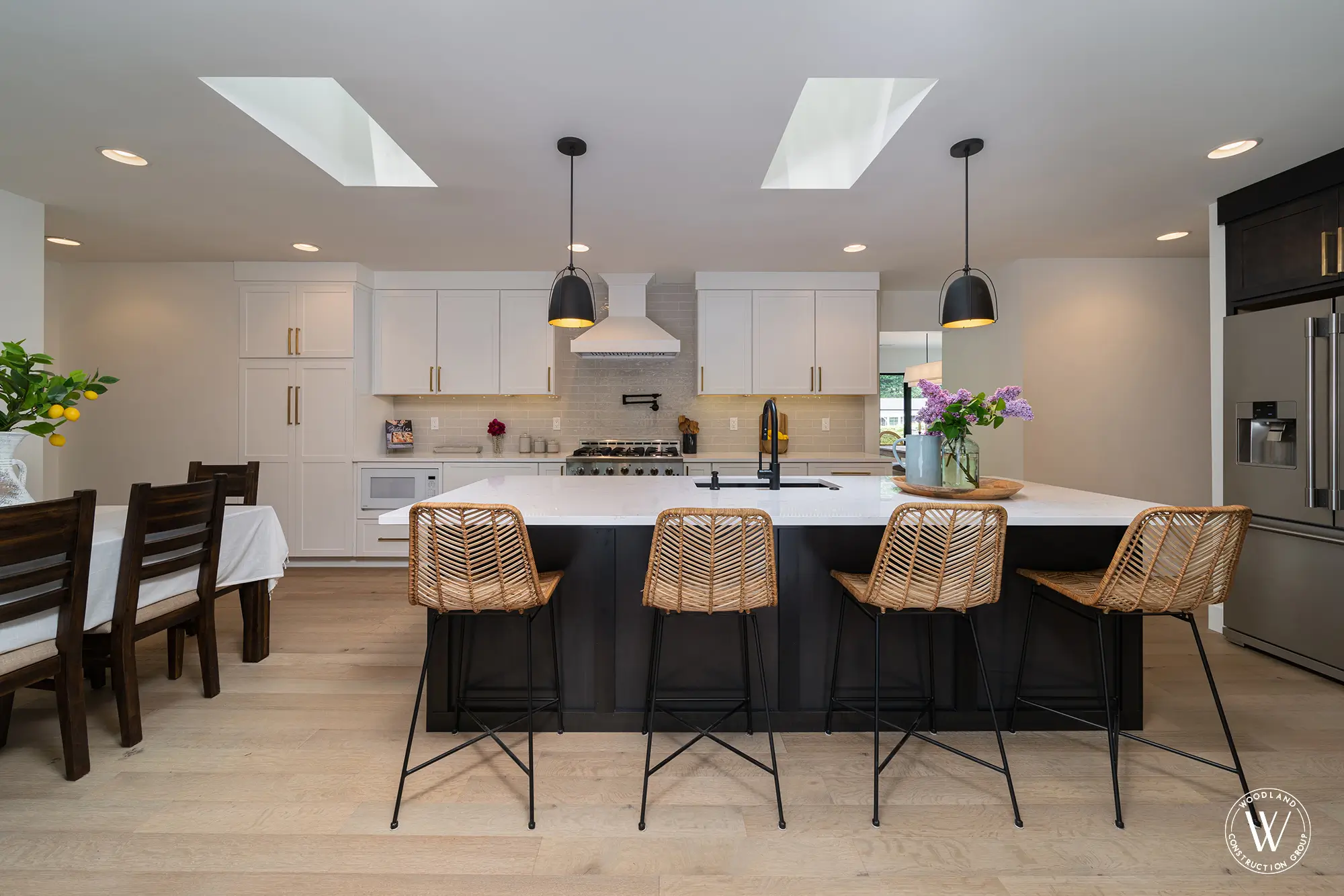 Whitepine kitchen with a custom white hood, gray subway tile and rattan counter stools at the island