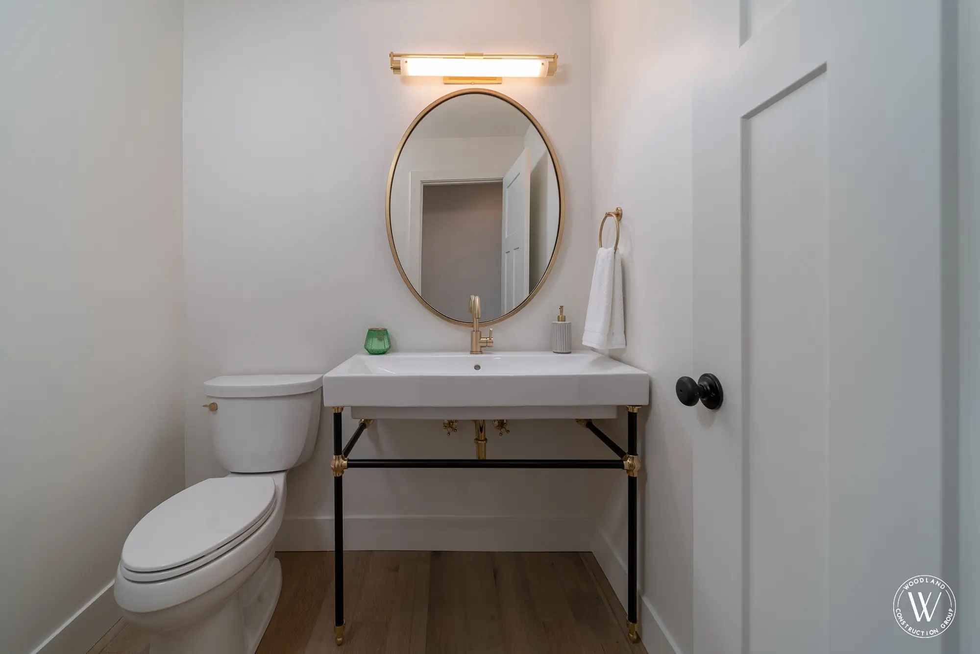 Whitepine powder room with a black-and-brass console sink and a round gold mirror