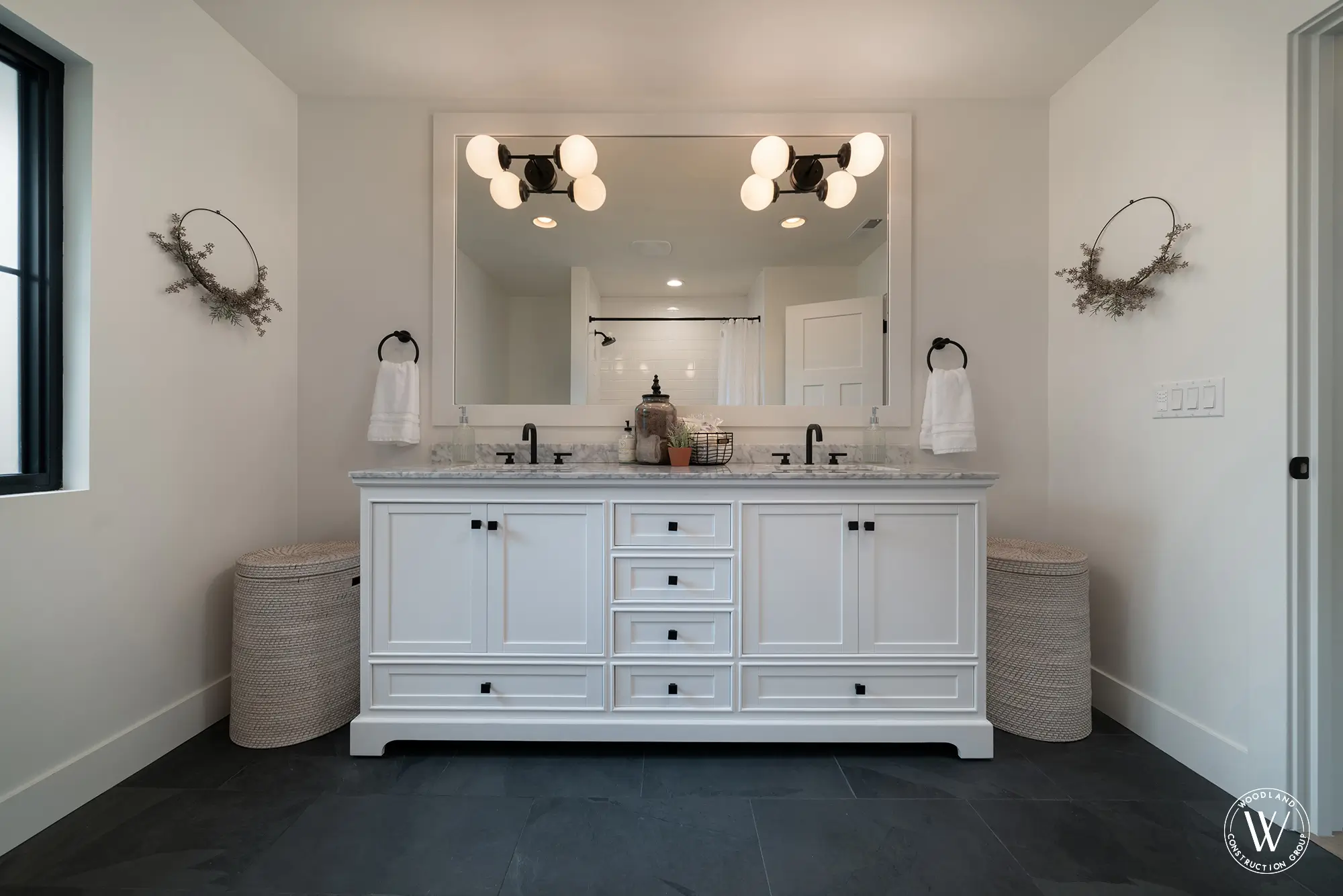 Whitepine primary bath with a white double vanity, marble tops, black hardware and a slate-tile floor