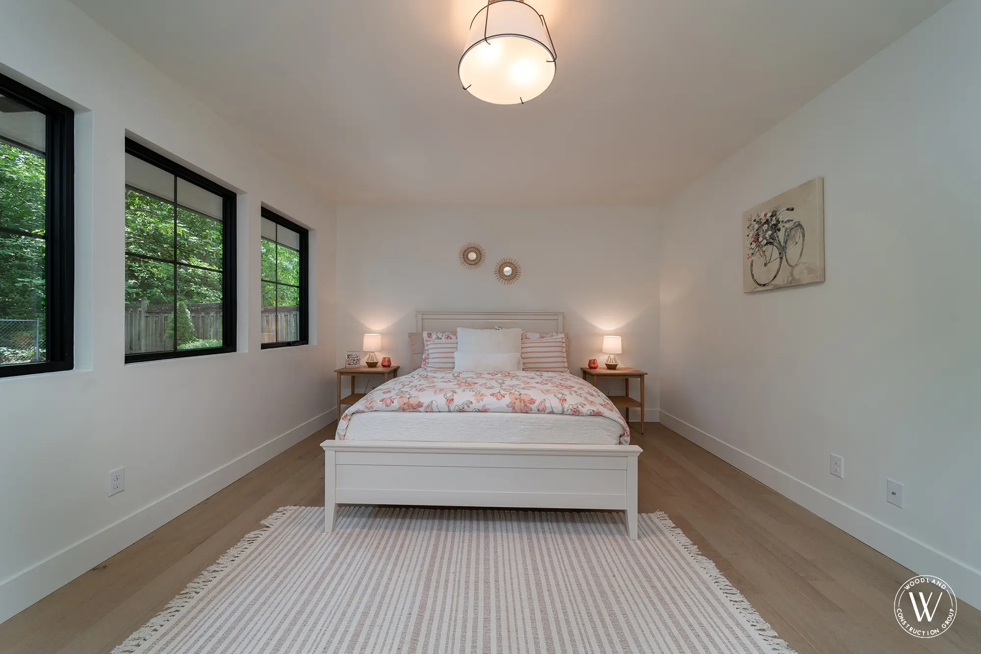 Whitepine bedroom with a white bed, floral bedding and a wall of black-framed windows onto the garden