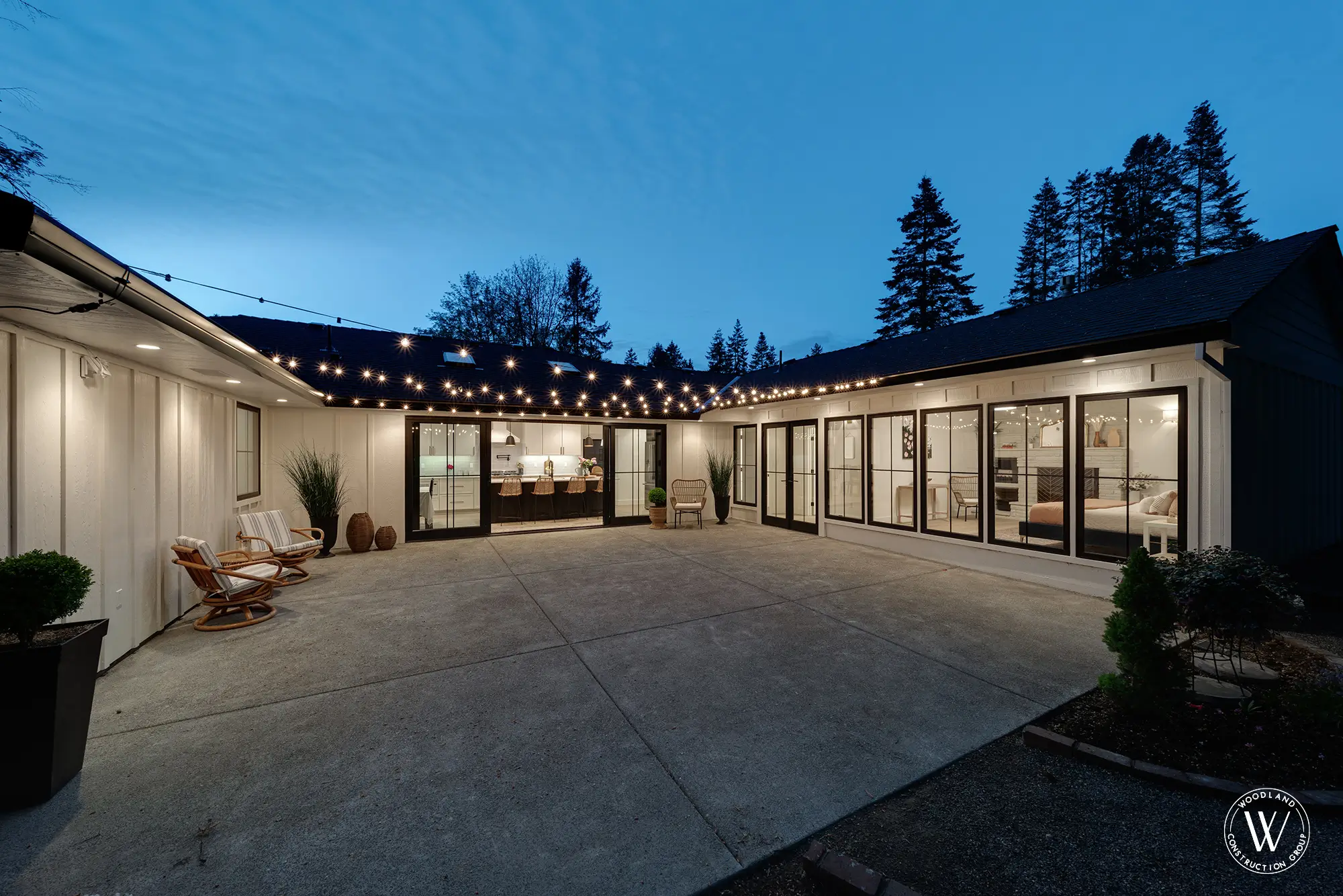 Whitepine mid-century ranch courtyard at twilight with string lights and glowing black-framed glass
