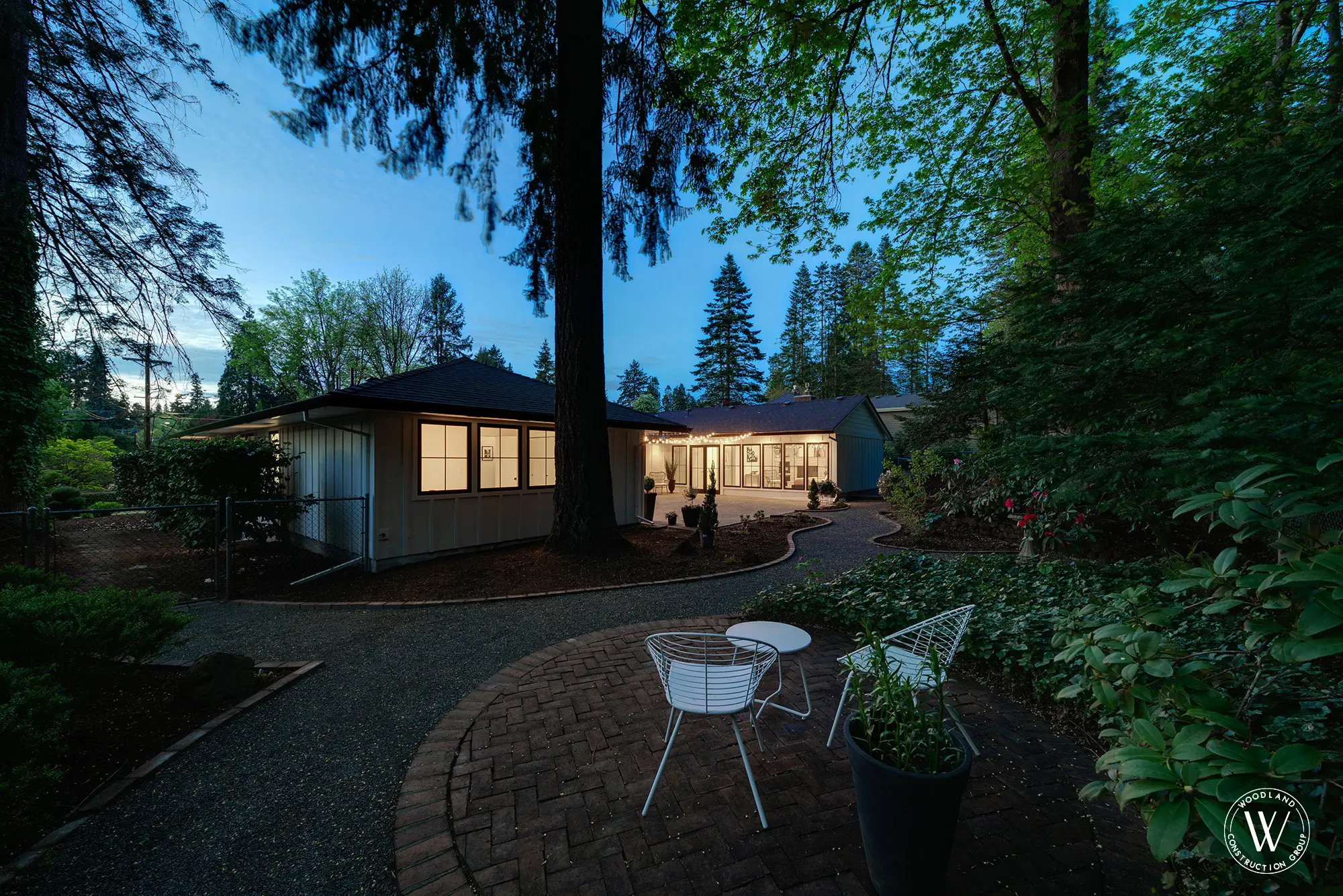 Whitepine back garden and brick patio under towering firs at dusk, SW Portland West Slope