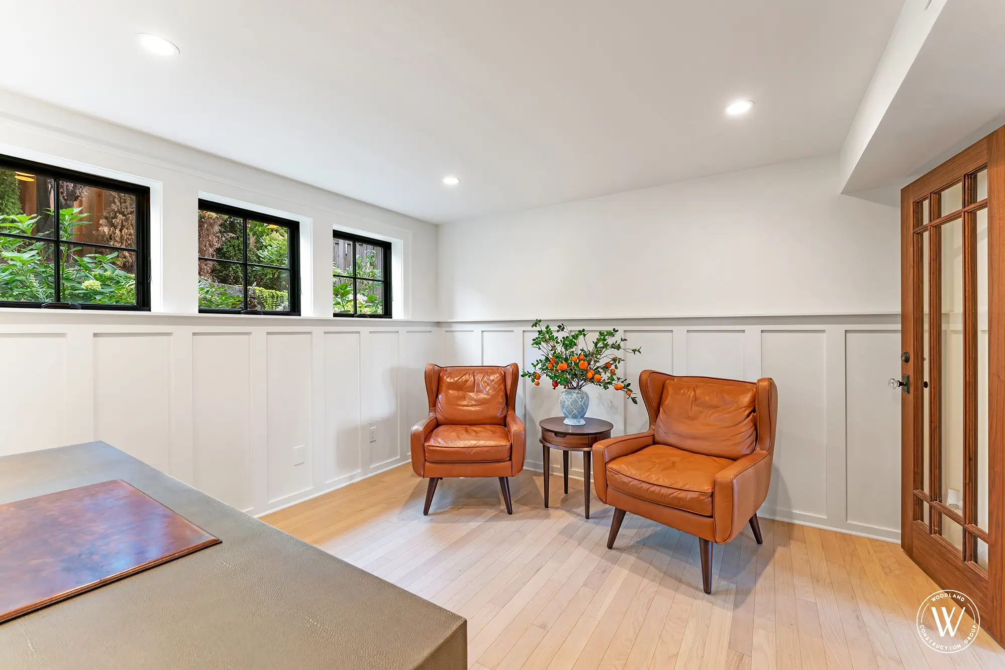 Berkshire sitting den with board-and-batten wainscot, clerestory windows and leather wingback chairs