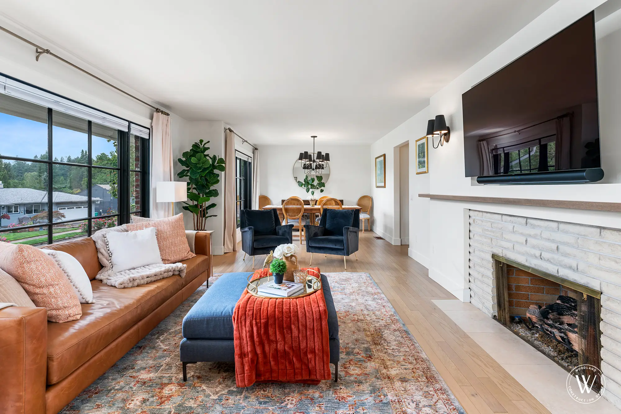 Berkshire living room with caramel leather sofa, refaced brick fireplace and open sightline to the dining area