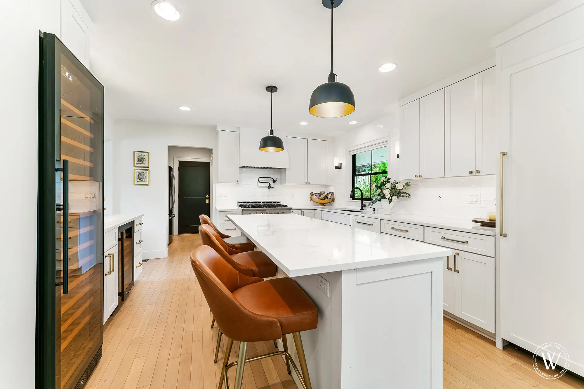 Berkshire kitchen island with quartz top, caramel leather counter stools and a tall built-in wine refrigerator