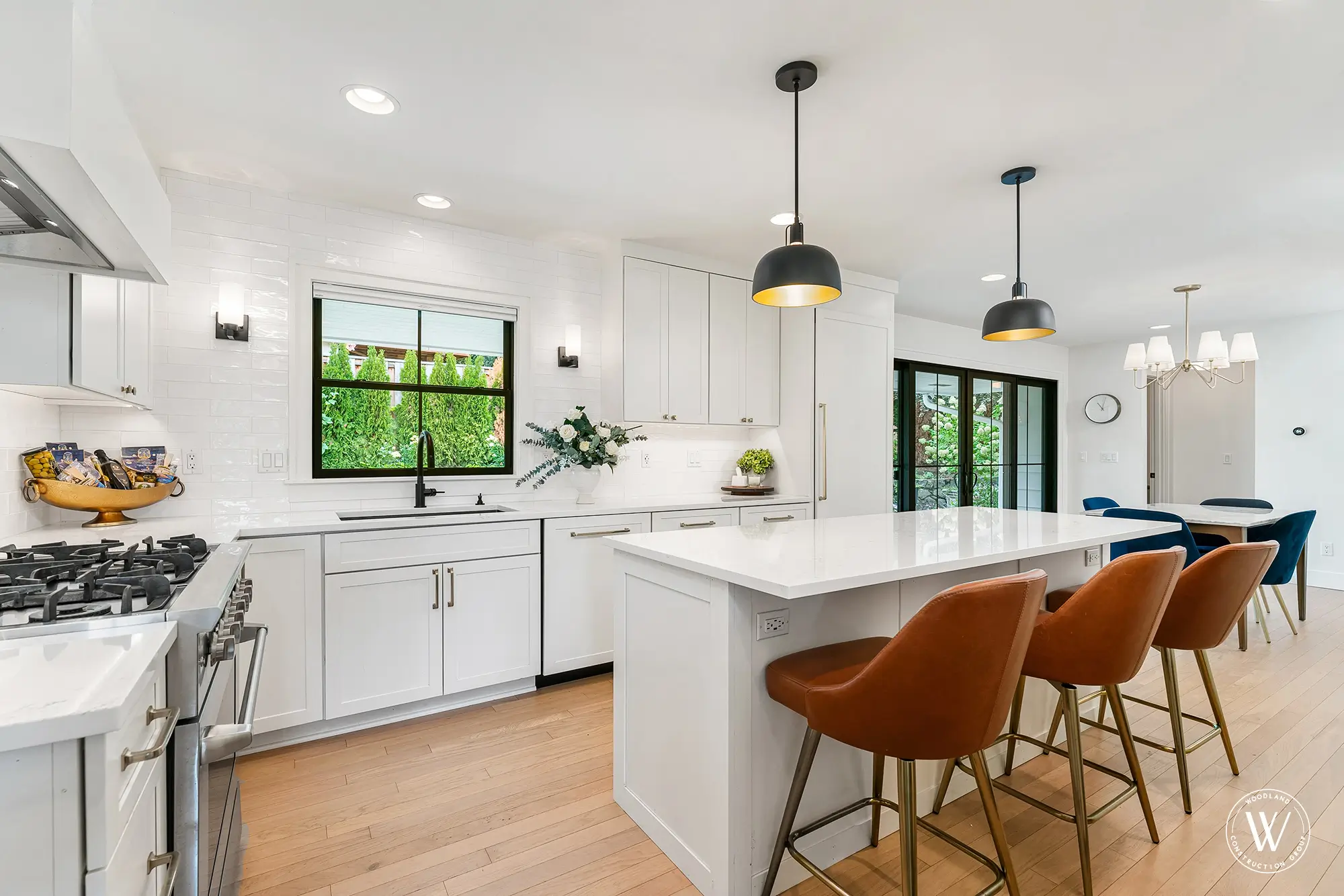 Restored Berkshire kitchen with white cabinetry, quartz island, professional gas range and black-framed windows, west-side Portland