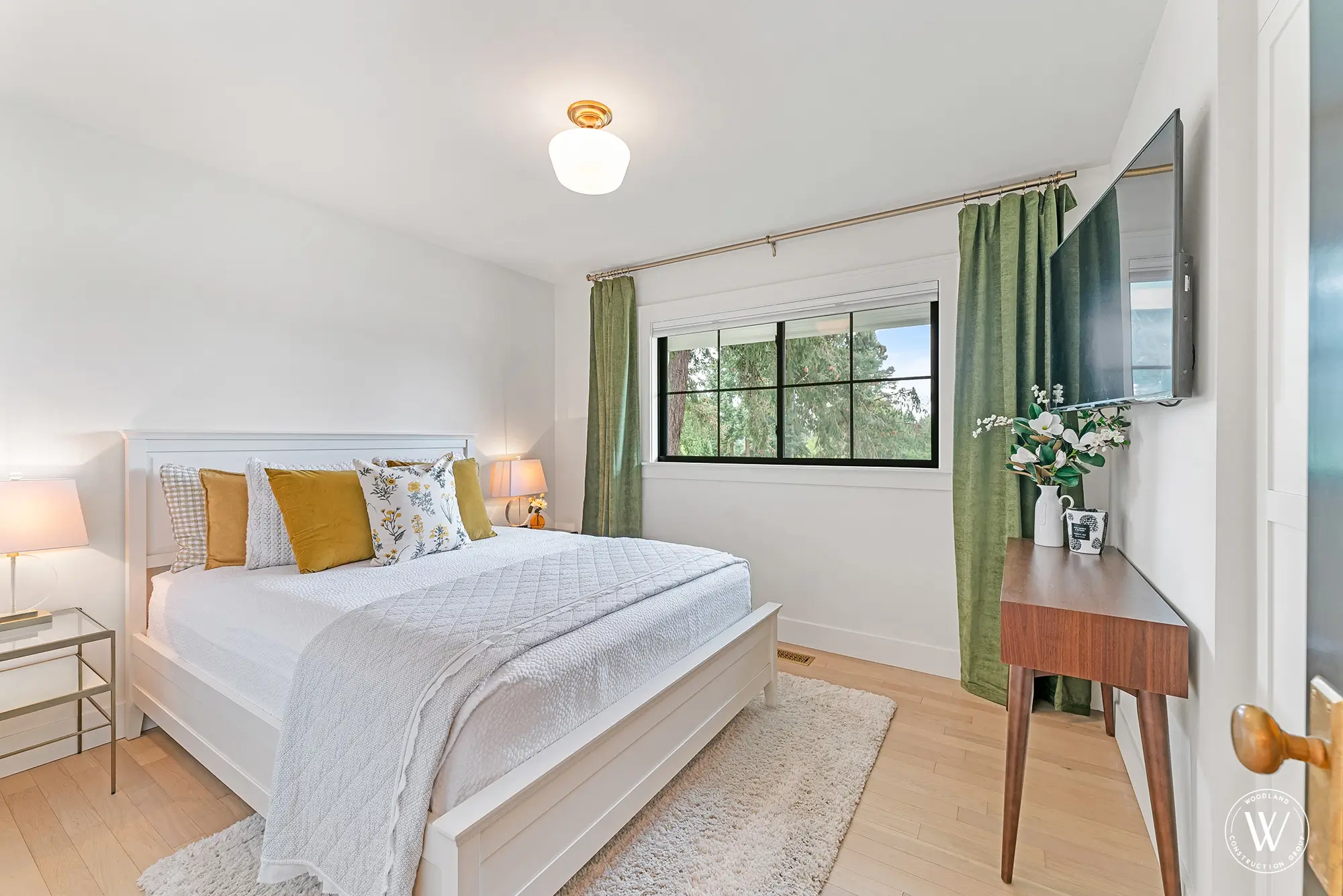 Berkshire bedroom with green drapery, mustard accents and a black-framed window over the treetops