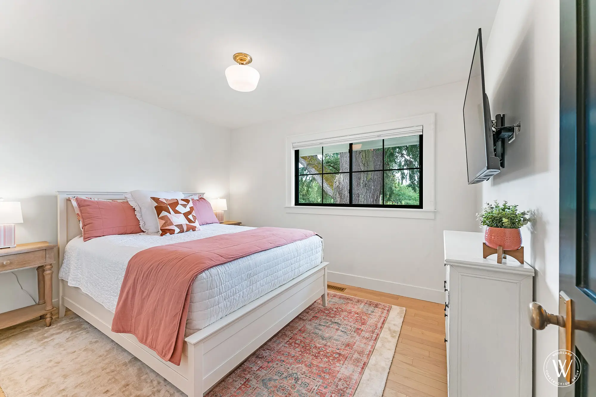 Berkshire bedroom in coral and cream tones with a large black-framed window looking onto a mature tree
