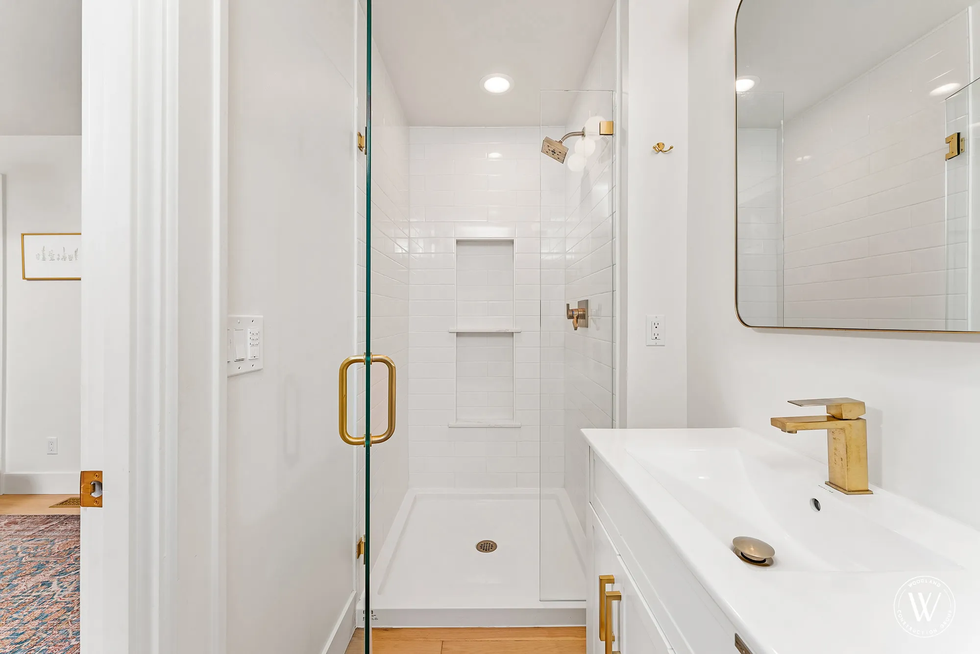 Berkshire en-suite bathroom with a glass walk-in subway-tile shower, brass hardware and floating vanity
