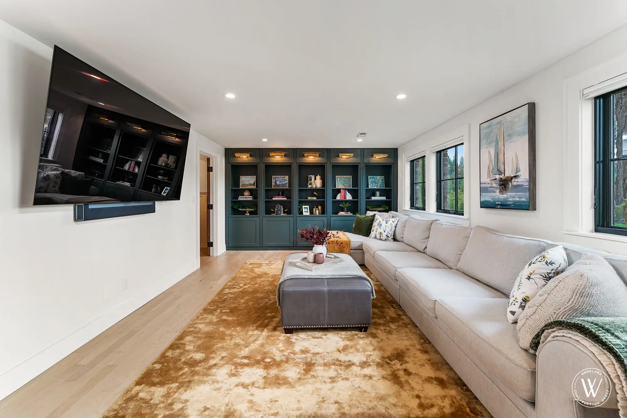 Berkshire lower-level family room with deep green built-in bookcase wall and a large sectional sofa