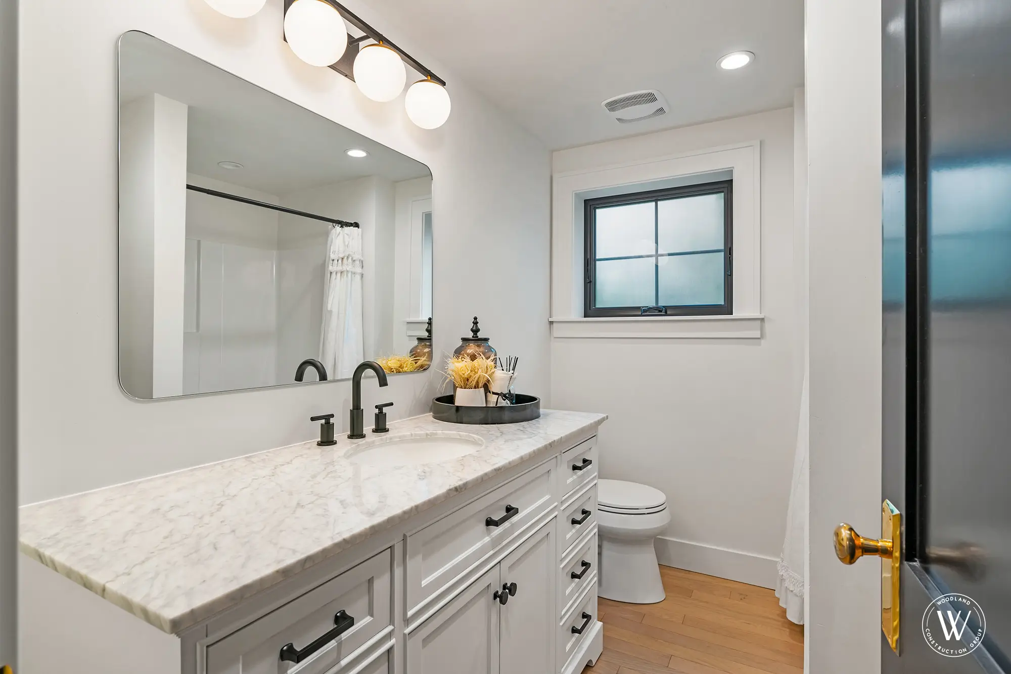 Berkshire bathroom with a marble-topped vanity, matte-black fixtures and hardware and an obscured privacy window