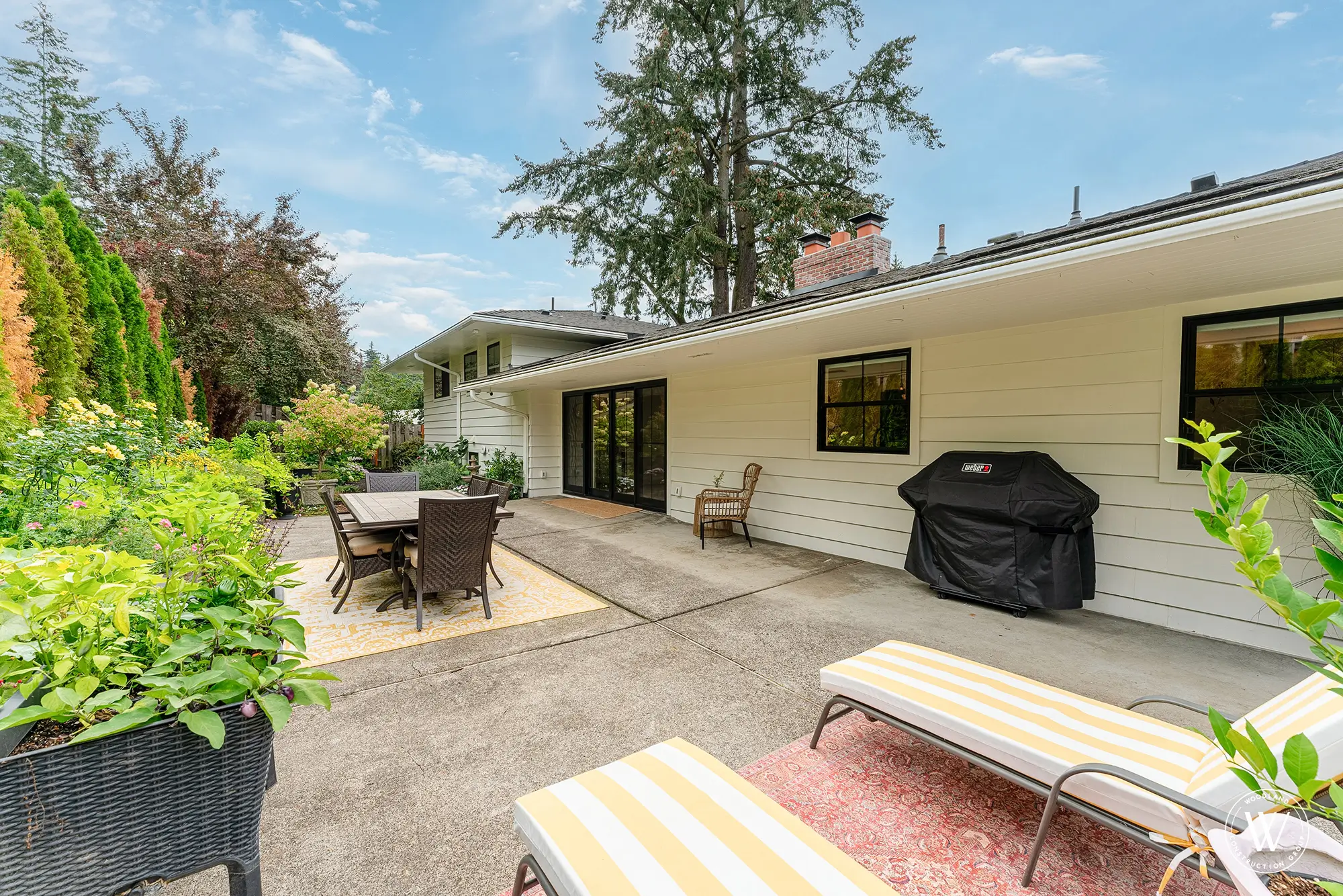 Rear exterior of the restored 1962 Berkshire split-level with patio dining, grill and a mature west-side Portland garden