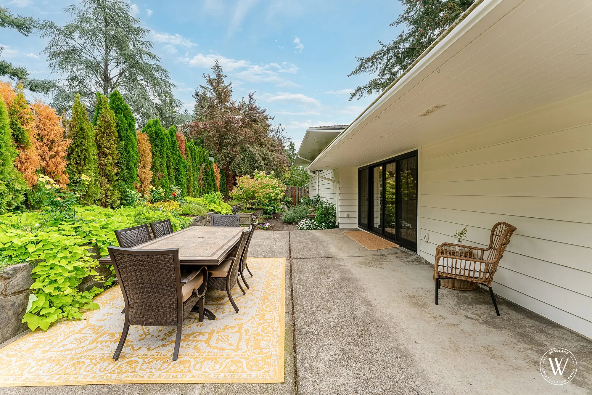 Berkshire backyard patio dining set framed by mature evergreens and the home's sliding glass doors