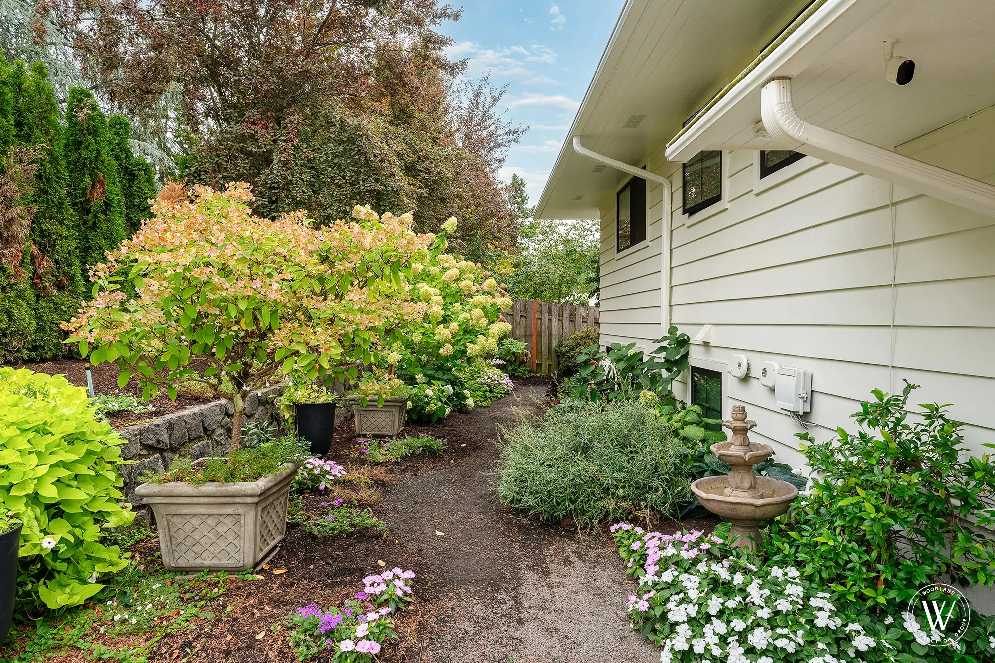 Side-yard garden path at the Berkshire home with hydrangeas, a tiered stone wall and a stone fountain